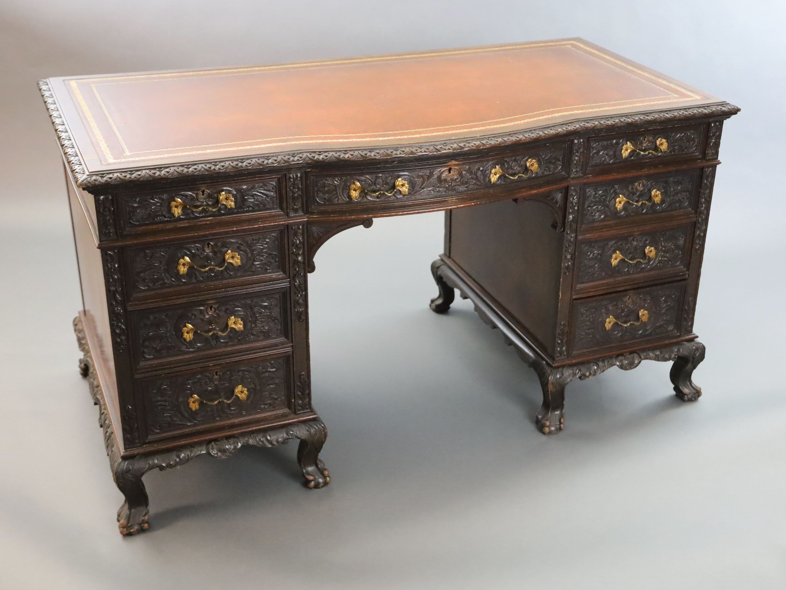 An Edwardian foliate carved mahogany serpentine kneehole desk, W.4ft 6in. D.2ft 5in. H.2ft 6in.